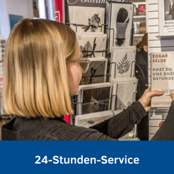 Foto einer jungen Frau, die vor einem Grußkartenständer steht. Beworben wird der 24-Stunden-Online-Service