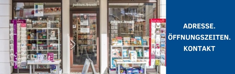Man sieht die Schaufenster der Buchhandlung von außen, davor Postkartenständer, HInweis auf die Kontaktdaten